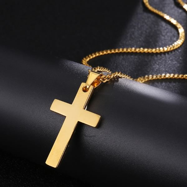 Elegantni zlatni privjesak križa na zlatnom lančiču, polegnut na crnoj koži